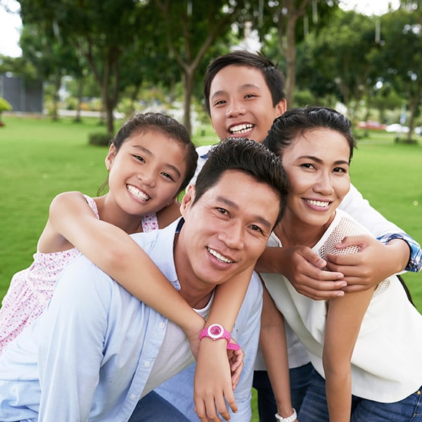 Family of four smiling in the park