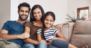 Family on a sofa embrace and smile after their dental exams.