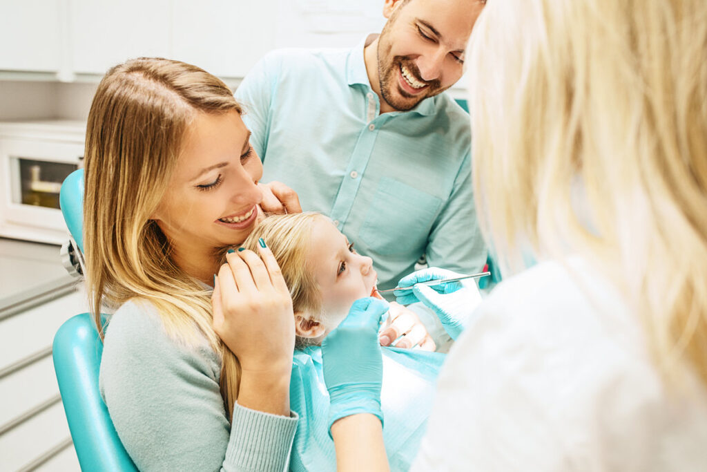 Dentist treating cute blonde child in his surgery.